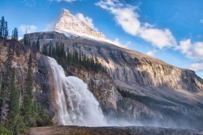 Emperor Falls beneath Mount Robson under sunny blue skies with mist from waterfall drifting to the right